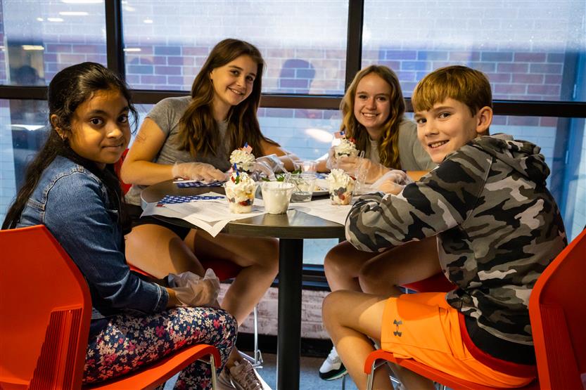 Four students smile while sitting at a table